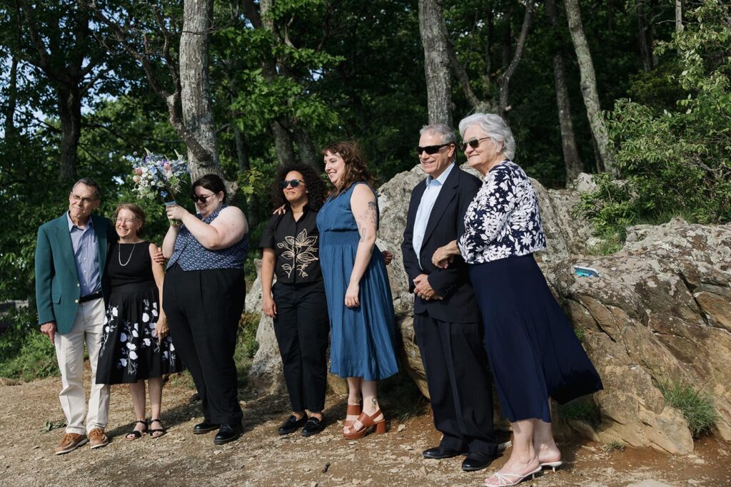 A couples family watches as they exchange vows. They are all smiling with excitement.