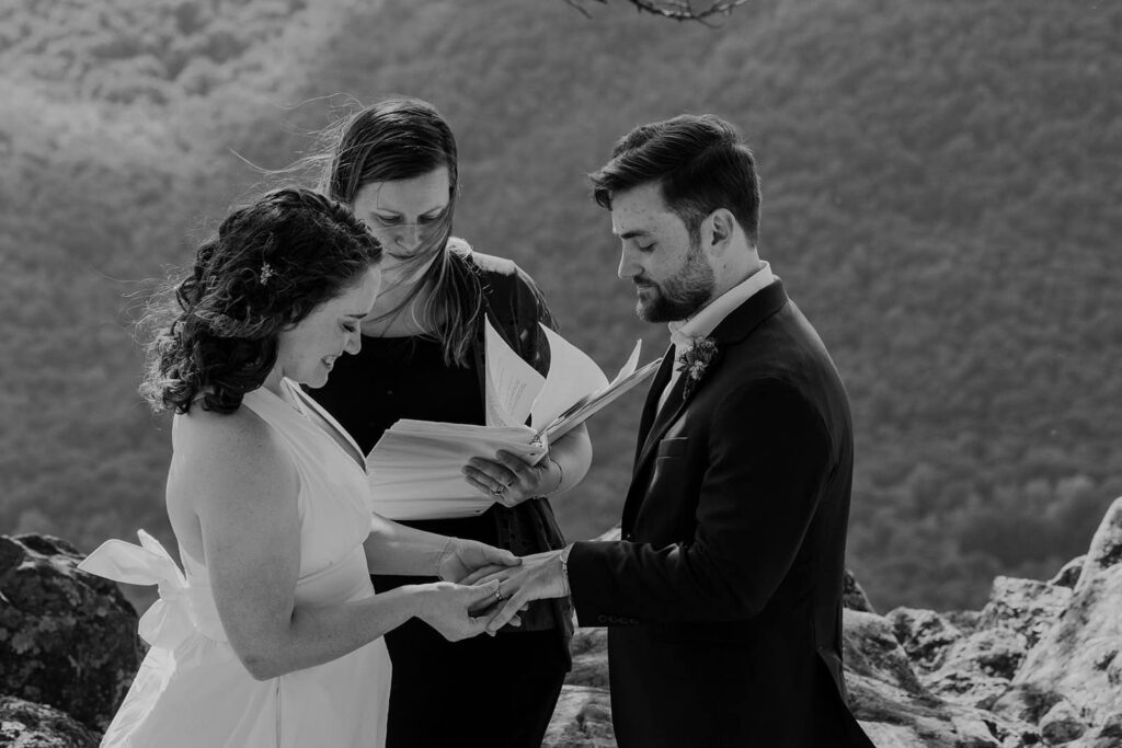 A bride places, a wedding ring on the groom's finger during their wedding ceremony in Virginia