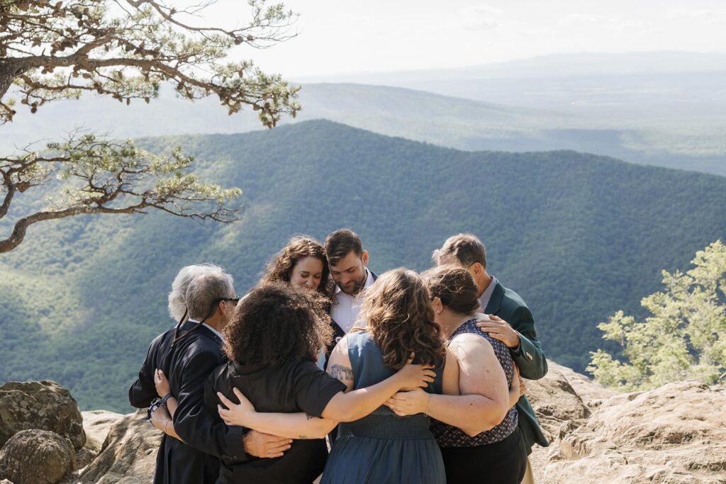A bride groom and their closest family members share a group hug at an overlook in Virginia after their elopement ceremony