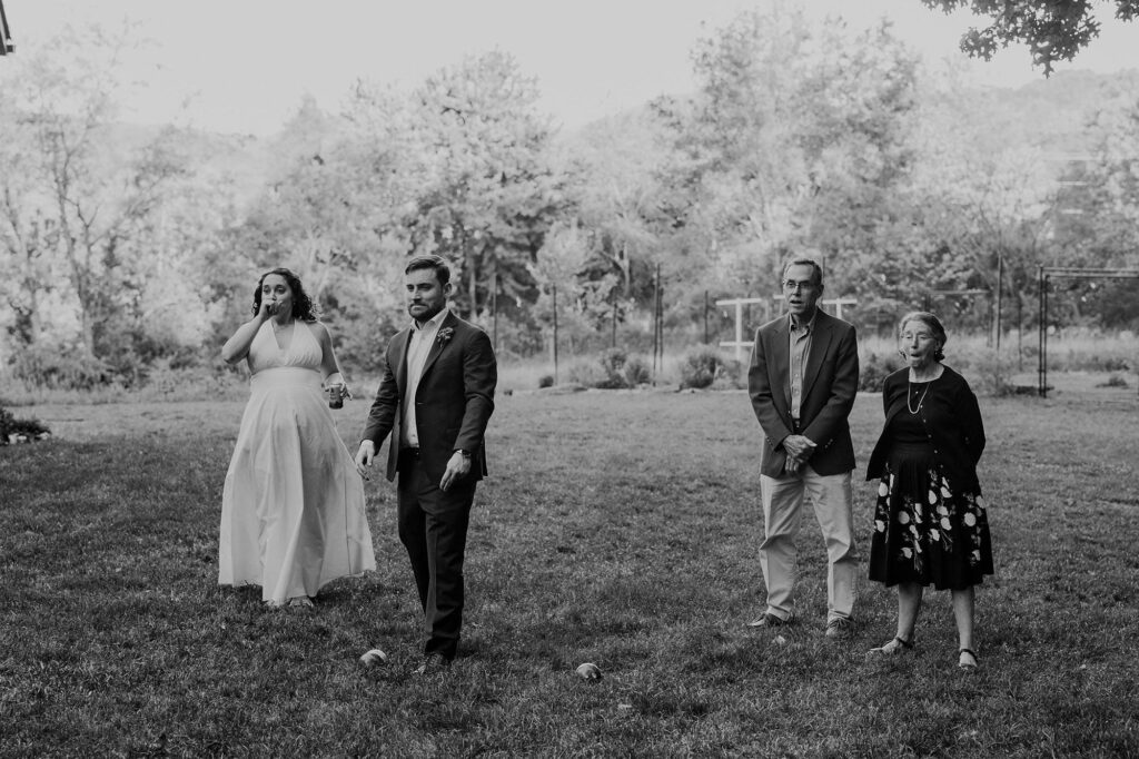 A photo of the reactions of a bride groom and her parents of the bad throw in the game of bocce by the groom during cocktail hour