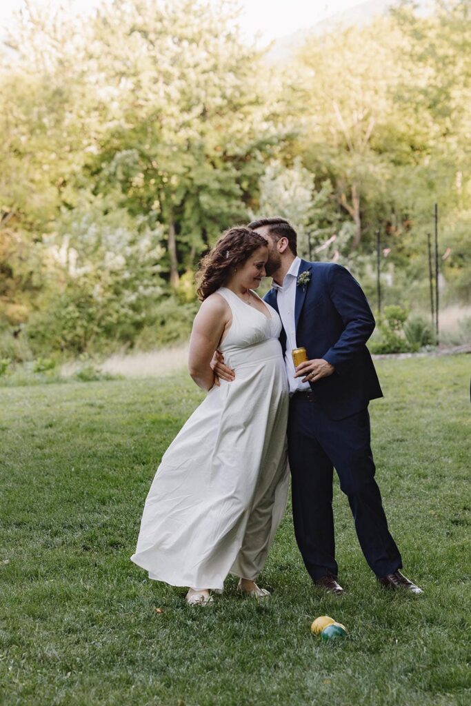 A groom leans into his wife, whispering in her ear during their intimate elopement reception at indigo house