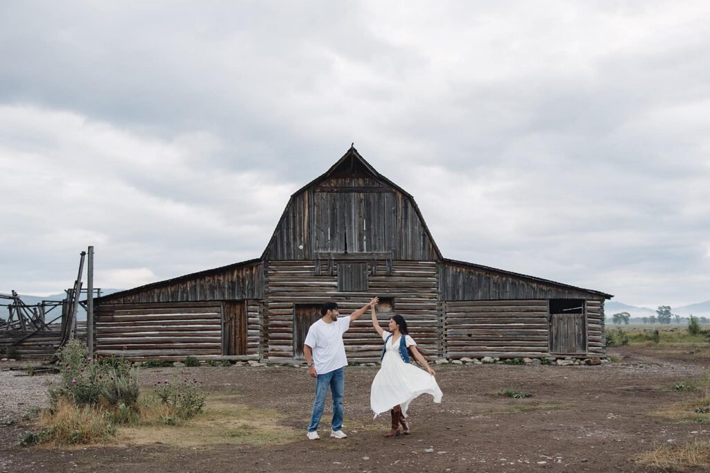 A couple spins in front of the barn at Mormons Row in Wyoming