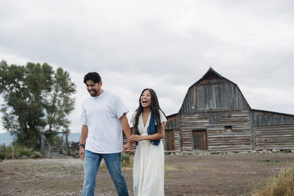 A couple walking in front of the barns at Mormon Row during an engagement session