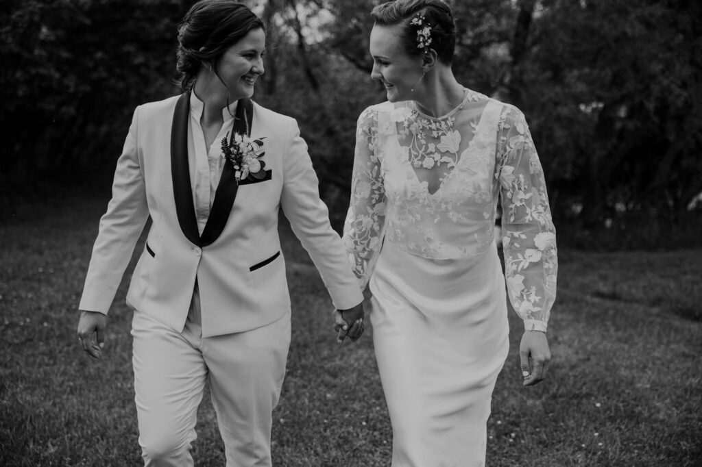 A couple holds hands and smiles while looking at one another during their full-day elopement