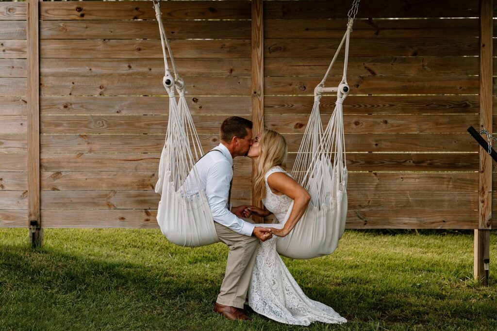A bride and groom sit in hammock swings and kiss during a relaxed part of their full-day elopement