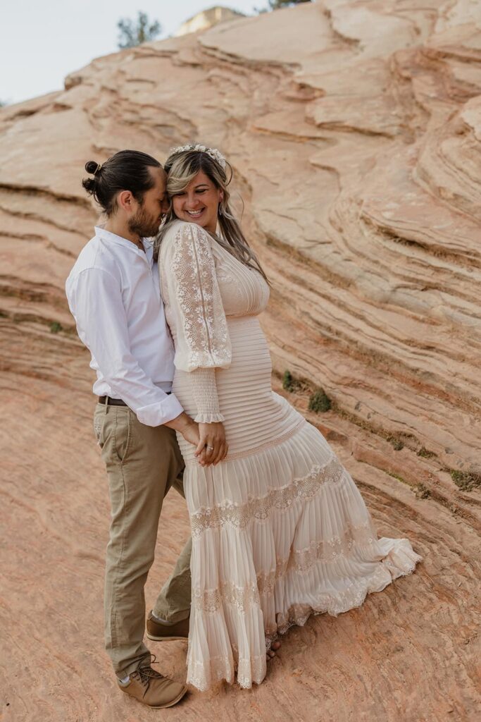 A groom snuggles into his bride during their elopement at Zion National Park